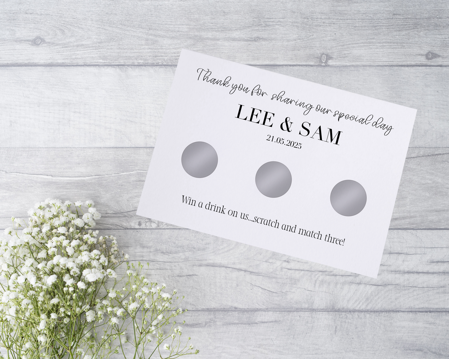 A close-up view of a beautifully designed scratch card with elegant typography and decorative elements. The scratch card features customised names and a wedding date, surrounded by symbols representing hidden prizes.