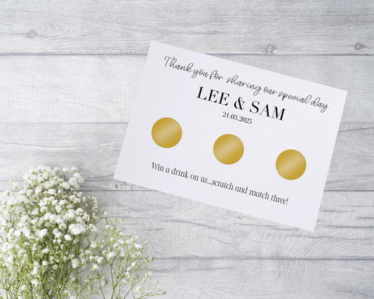  A close-up view of a beautifully designed scratch card with elegant typography and decorative elements. The scratch card features customised names and a wedding date, surrounded by symbols representing hidden prizes.
