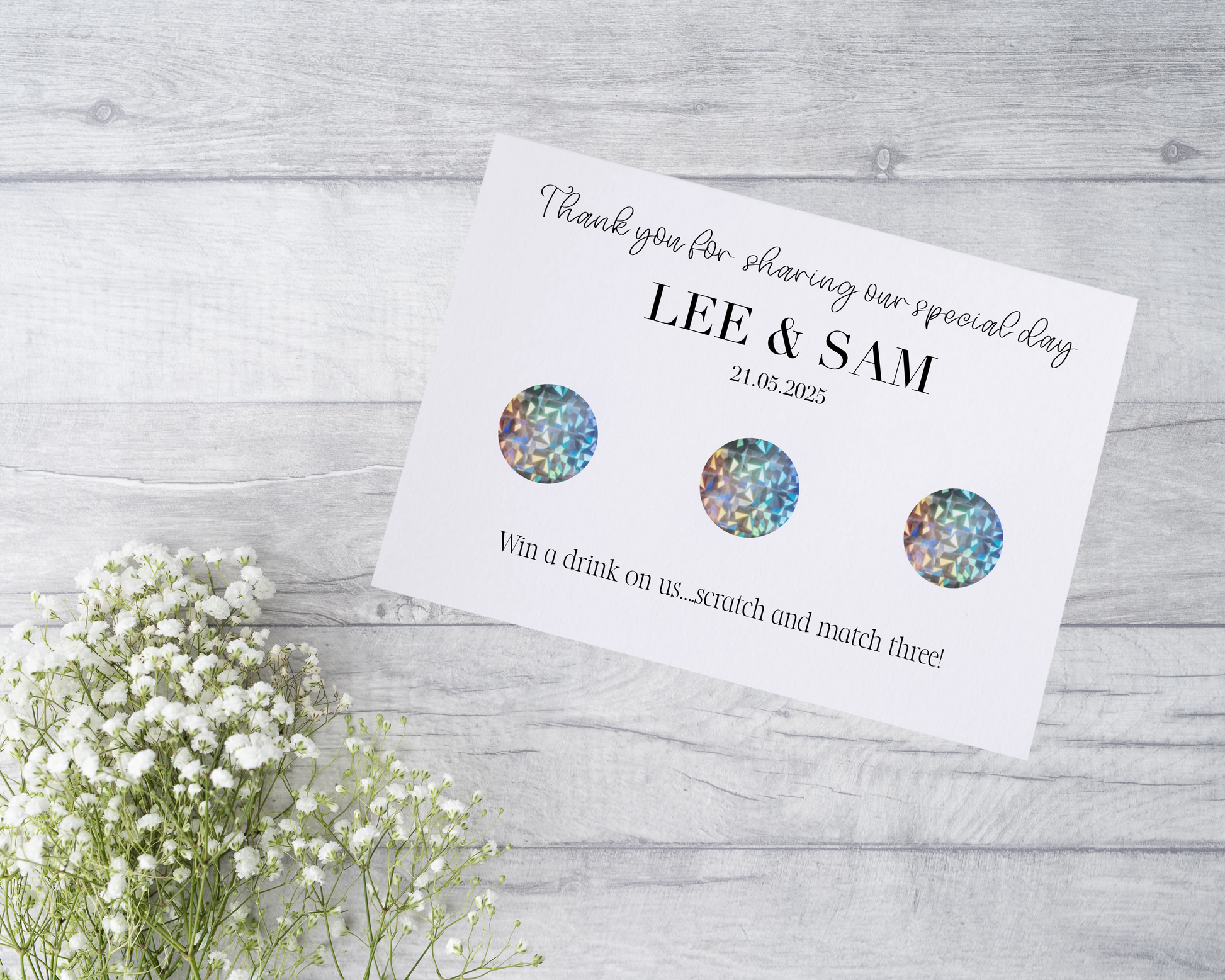  A close-up view of a beautifully designed scratch card with elegant typography and decorative elements. The scratch card features customised names and a wedding date, surrounded by symbols representing hidden prizes.