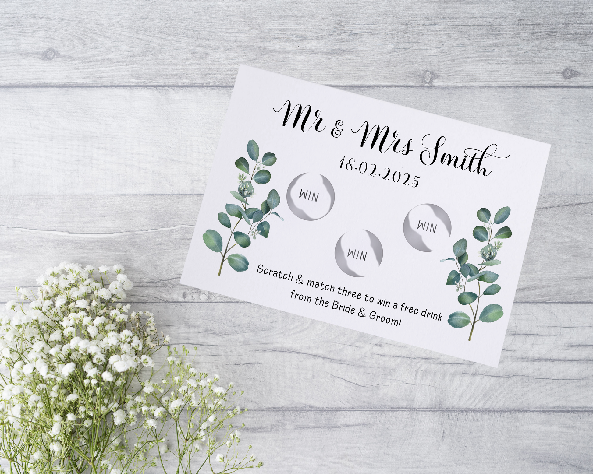  A close-up view of a beautifully designed scratch card with elegant typography and decorative elements. The scratch card features customised names and a wedding date, surrounded by symbols representing hidden prizes.