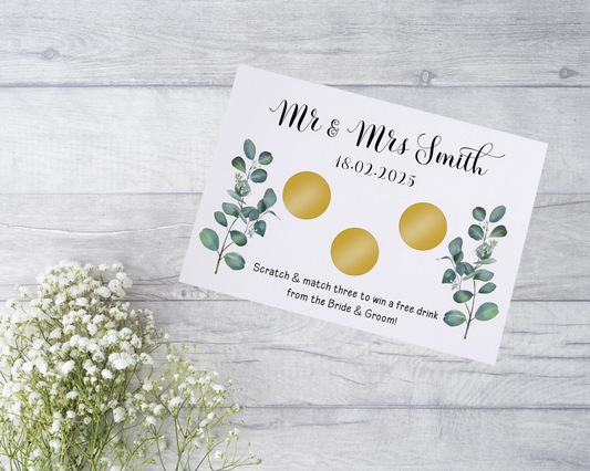  A close-up view of a beautifully designed scratch card with elegant typography and decorative elements. The scratch card features customised names and a wedding date, surrounded by symbols representing hidden prizes.