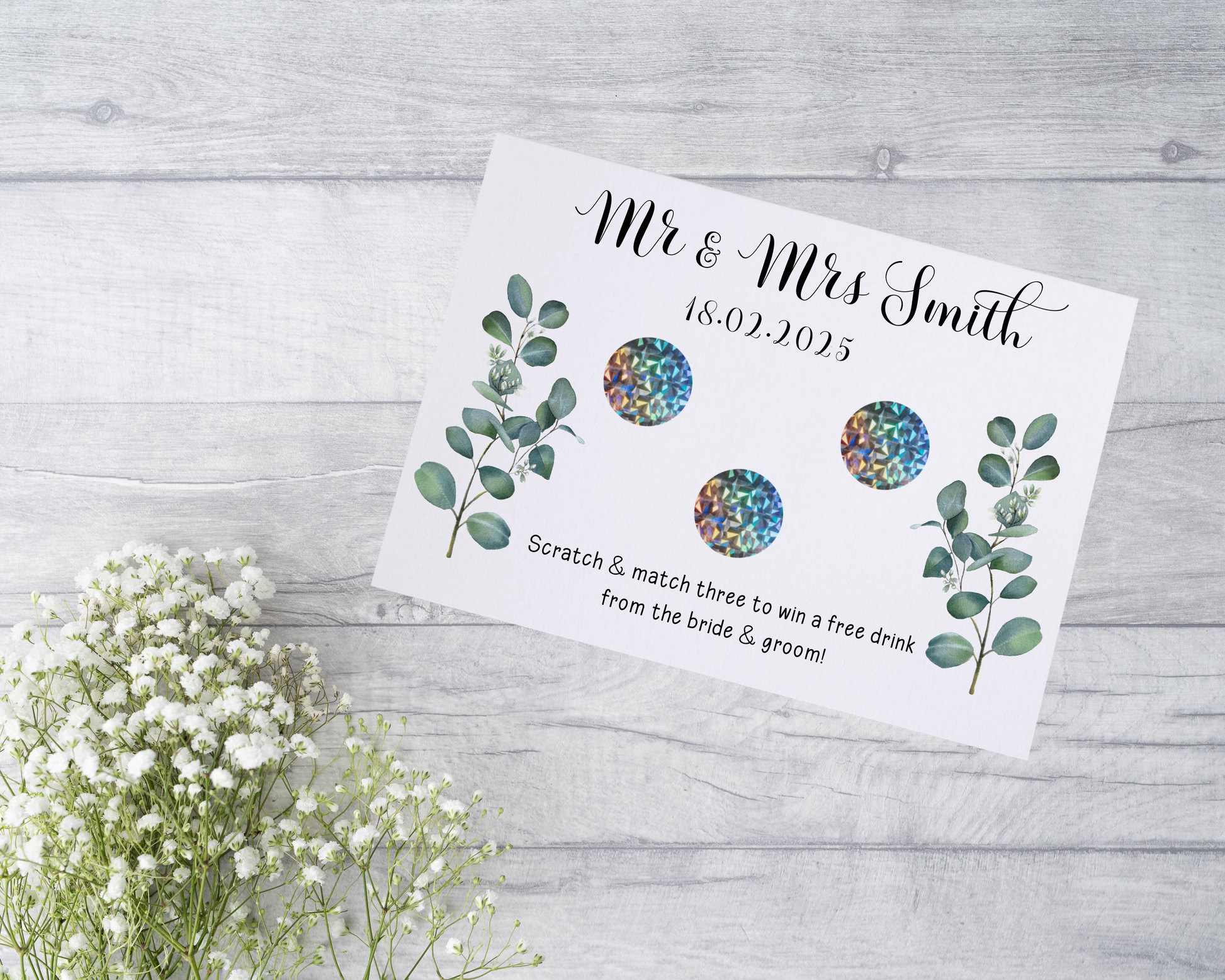  A close-up view of a beautifully designed scratch card with elegant typography and decorative elements. The scratch card features customised names and a wedding date, surrounded by symbols representing hidden prizes.