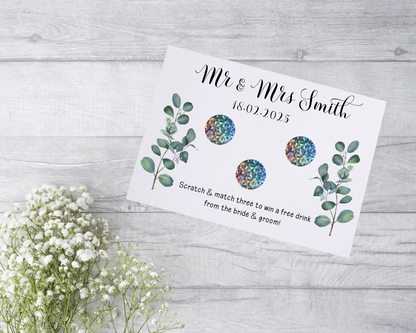  A close-up view of a beautifully designed scratch card with elegant typography and decorative elements. The scratch card features customised names and a wedding date, surrounded by symbols representing hidden prizes.