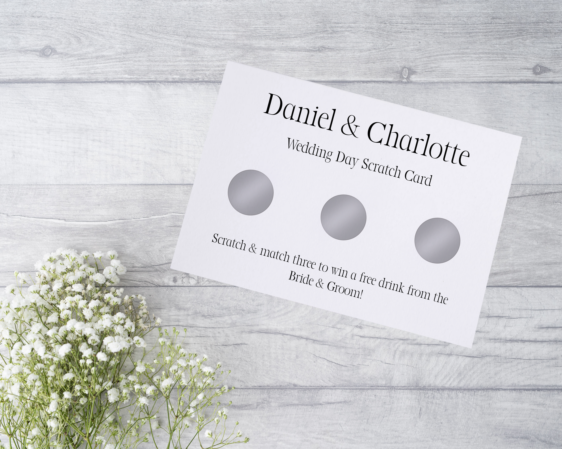  A close-up view of a beautifully designed scratch card with elegant typography and decorative elements. The scratch card features customised names and a wedding date, surrounded by symbols representing hidden prizes.
