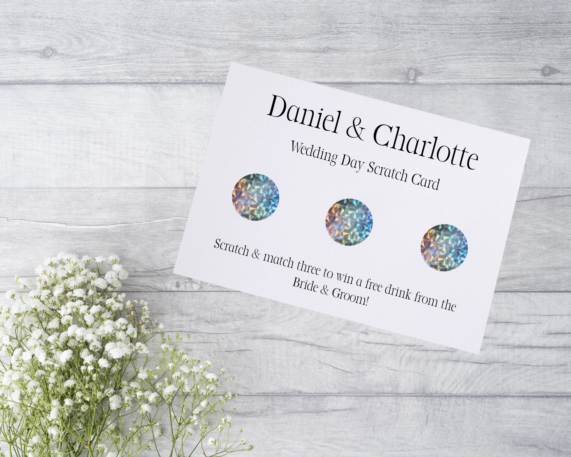 A close-up view of a beautifully designed scratch card with elegant typography and decorative elements. The scratch card features customised names and a wedding date, surrounded by symbols representing hidden prizes.