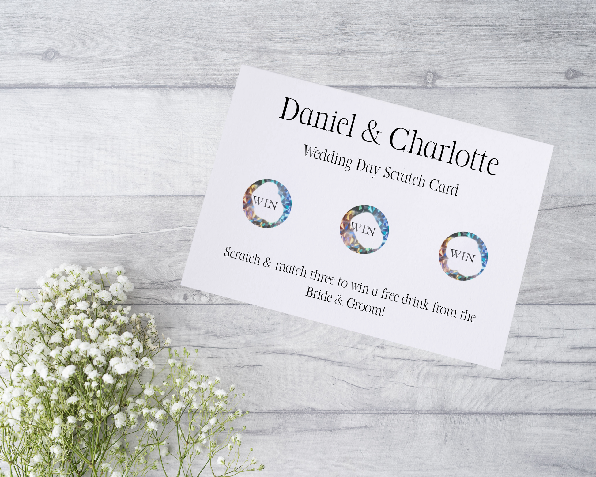  A close-up view of a beautifully designed scratch card with elegant typography and decorative elements. The scratch card features customised names and a wedding date, surrounded by symbols representing hidden prizes.