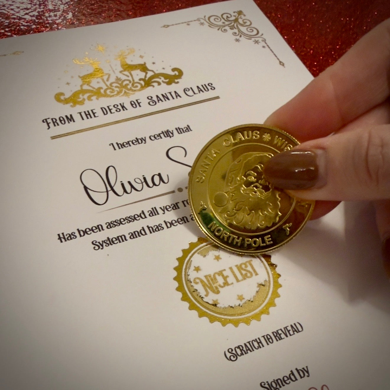 Gold coin with 'North Pole' text held over a certificate from Santa Claus