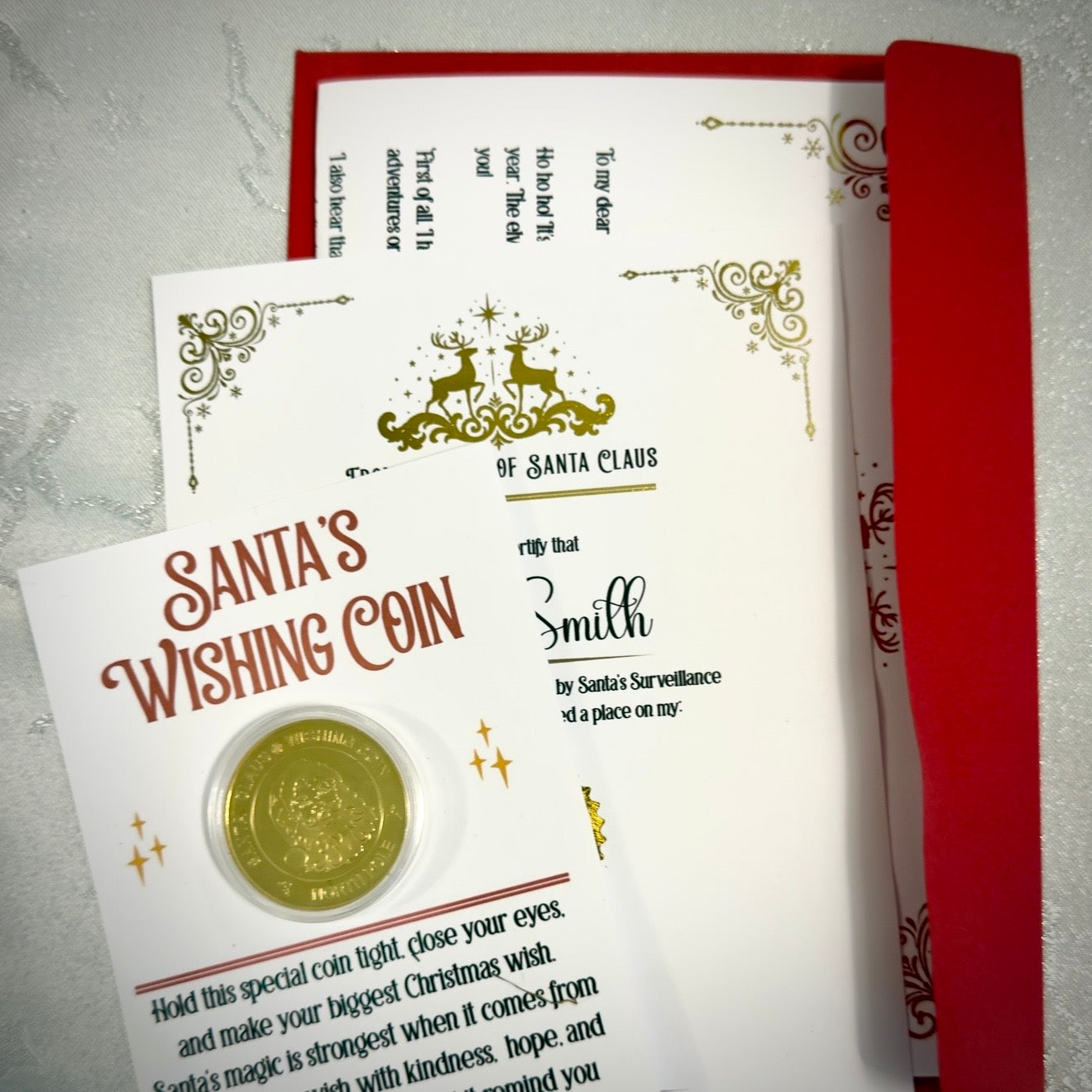 Santa's Wishing Coin with a card and red envelope on a light gray background